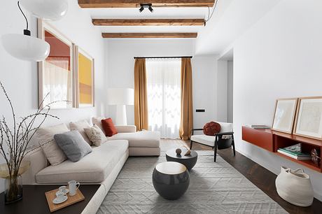 Modern living room with exposed wood beams, light furnishings, and decorative accents.