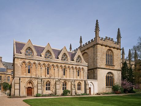 A majestic Gothic cathedral featuring ornate spires, arched windows, and a lush green lawn.