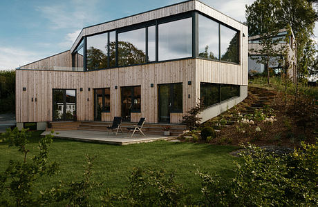 Modern wooden and glass exterior with a spacious deck and lush garden surroundings.