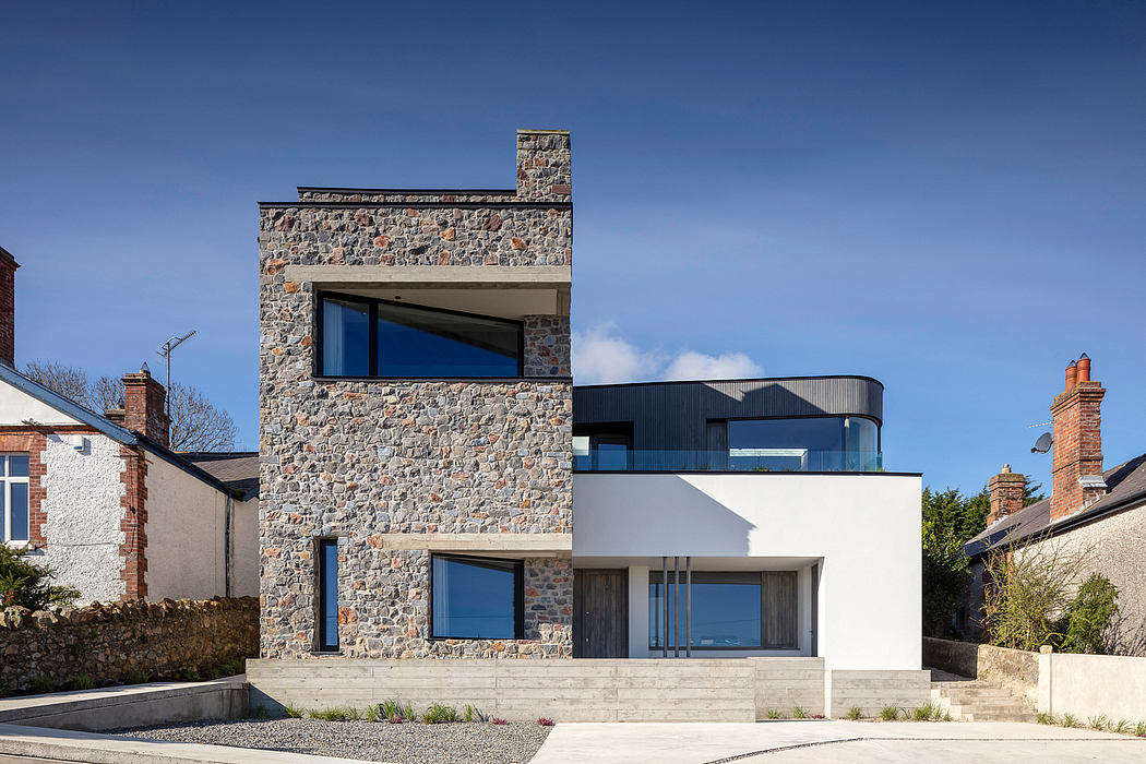 Modern two-story home with stone facade, large windows, and minimalist design elements.
