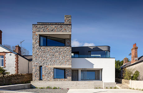 Modern two-story home with stone facade, large windows, and minimalist design elements.