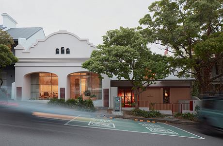 Historic building with arched windows and decorative exterior, flanked by lush trees.