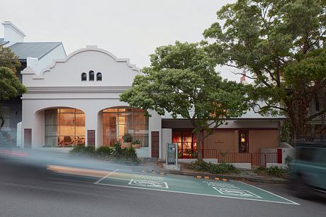 Historic building with arched windows and decorative exterior, flanked by lush trees.