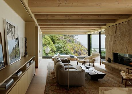 Cozy living room with wood-beamed ceiling, plush seating, and panoramic view of lush hillside.