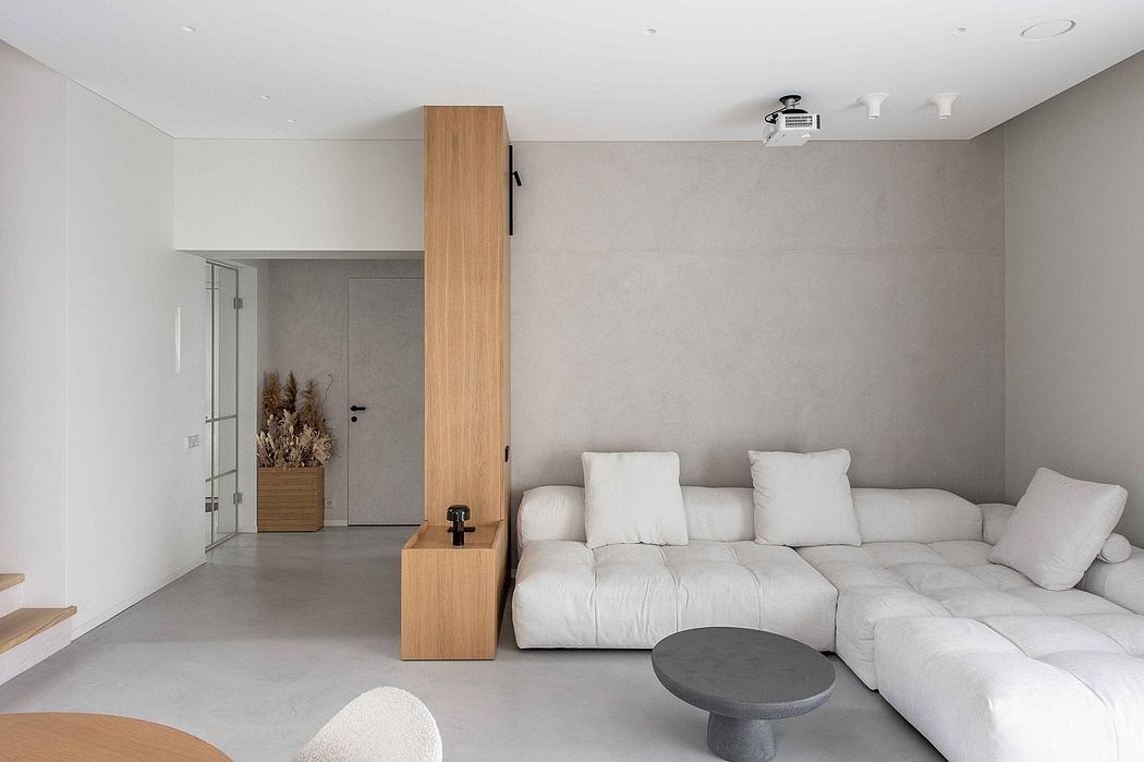 Minimalist living room with a modular white sofa, concrete floor, and wooden accents.