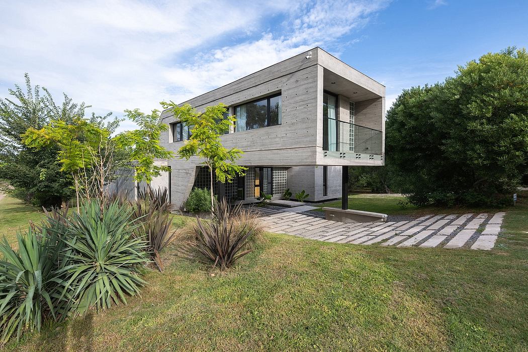 Modern two-story home with grey wood siding, large windows, and a well-landscaped yard.