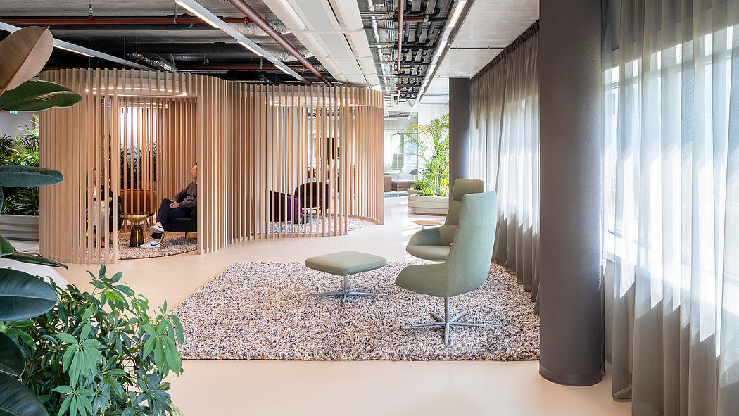Modern, minimalist office interior with wood slat partitions, cozy furniture, and lush plant life.
