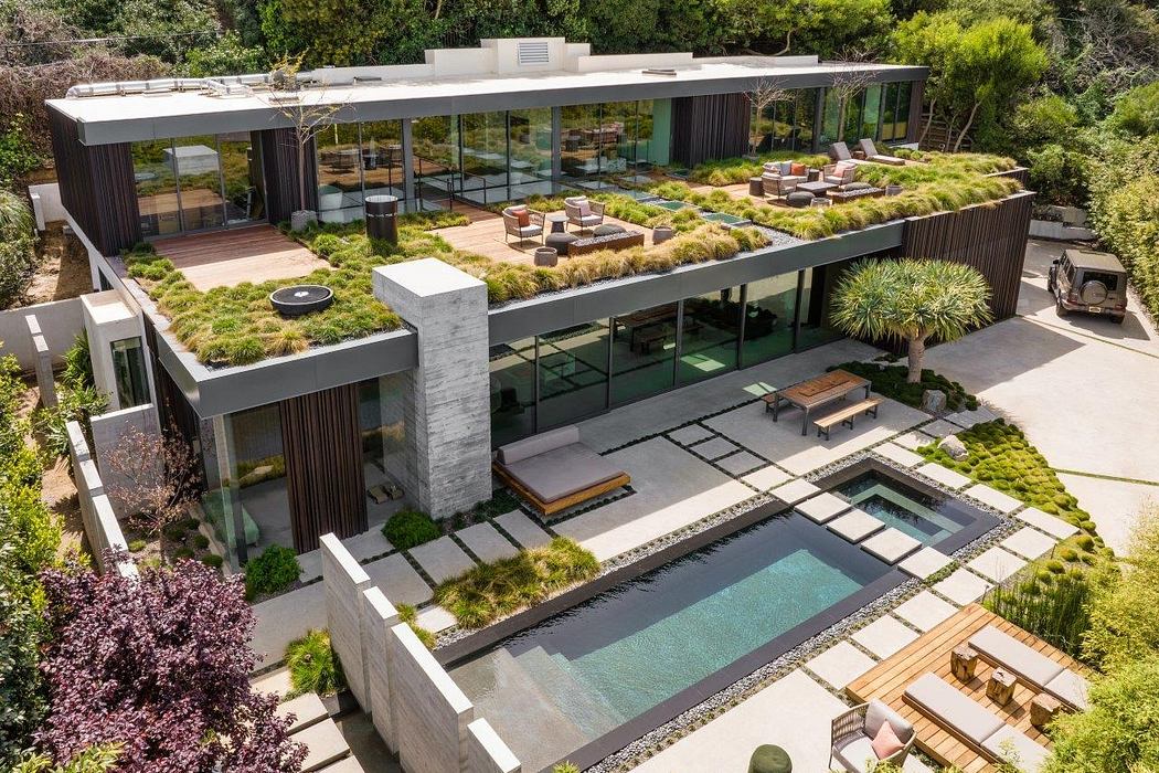 This modern architectural home features a lush, tiered garden with a sleek glass facade.