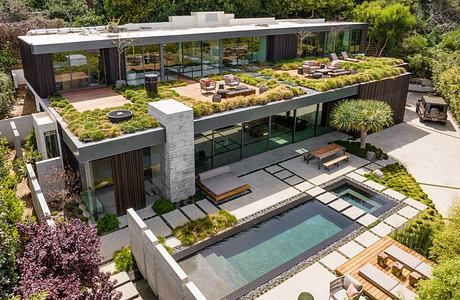 This modern architectural home features a lush, tiered garden with a sleek glass facade.