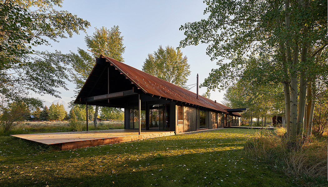 A rustic wooden structure with a sloping roof and covered porch, surrounded by lush greenery.