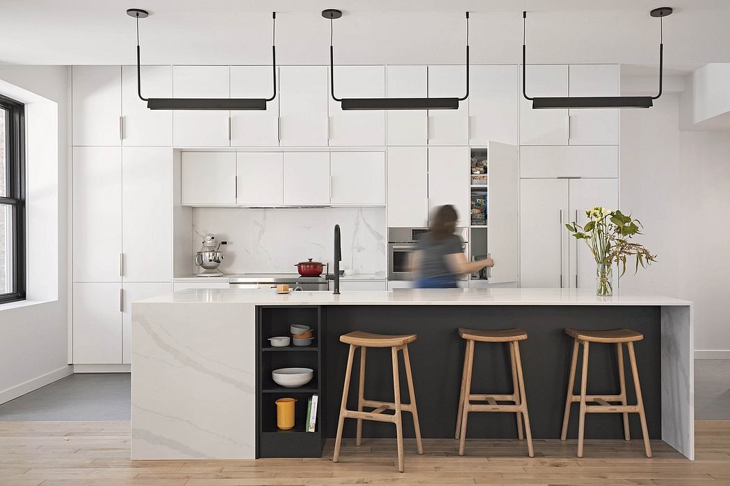 Modern kitchen with sleek white cabinets, black island, and wood bar stools. Minimalist lighting fixtures.