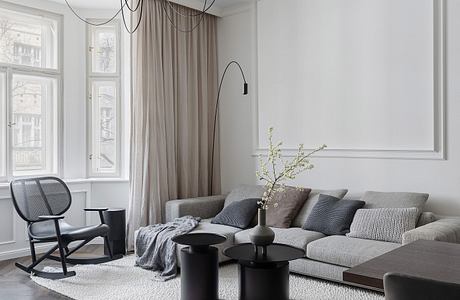 Spacious living room with large windows, modern chandelier, and textured area rug.