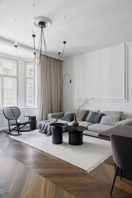 Spacious living room with large windows, modern chandelier, and textured area rug.