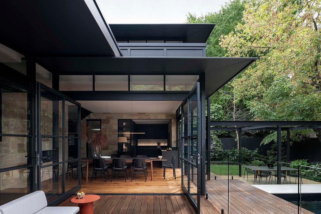 A striking modern pavilion with expansive glass walls, wood decking, and lush greenery.