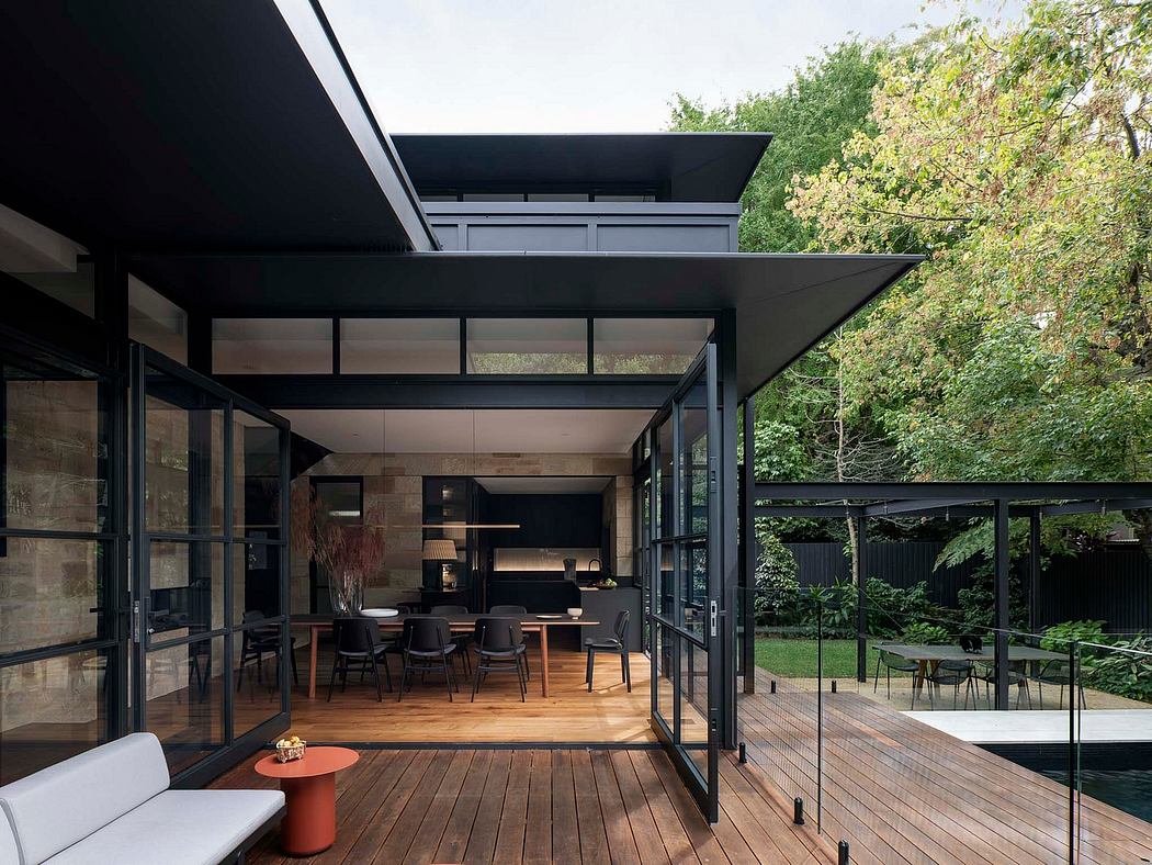 A striking modern pavilion with expansive glass walls, wood decking, and lush greenery.