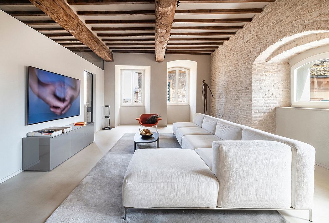 Spacious living room with exposed wooden beams, brick walls, and a large modern TV.