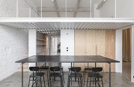 Large modern workspace with concrete ceiling, metallic shelves, and wooden panels.