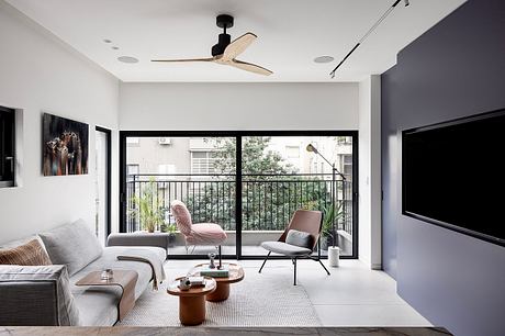 Minimalist living room with modern furniture, large windows, and a sleek ceiling fan.