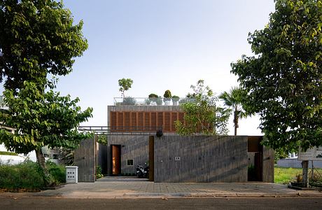 Modern residential building with concrete exterior, wooden screens, and rooftop garden.