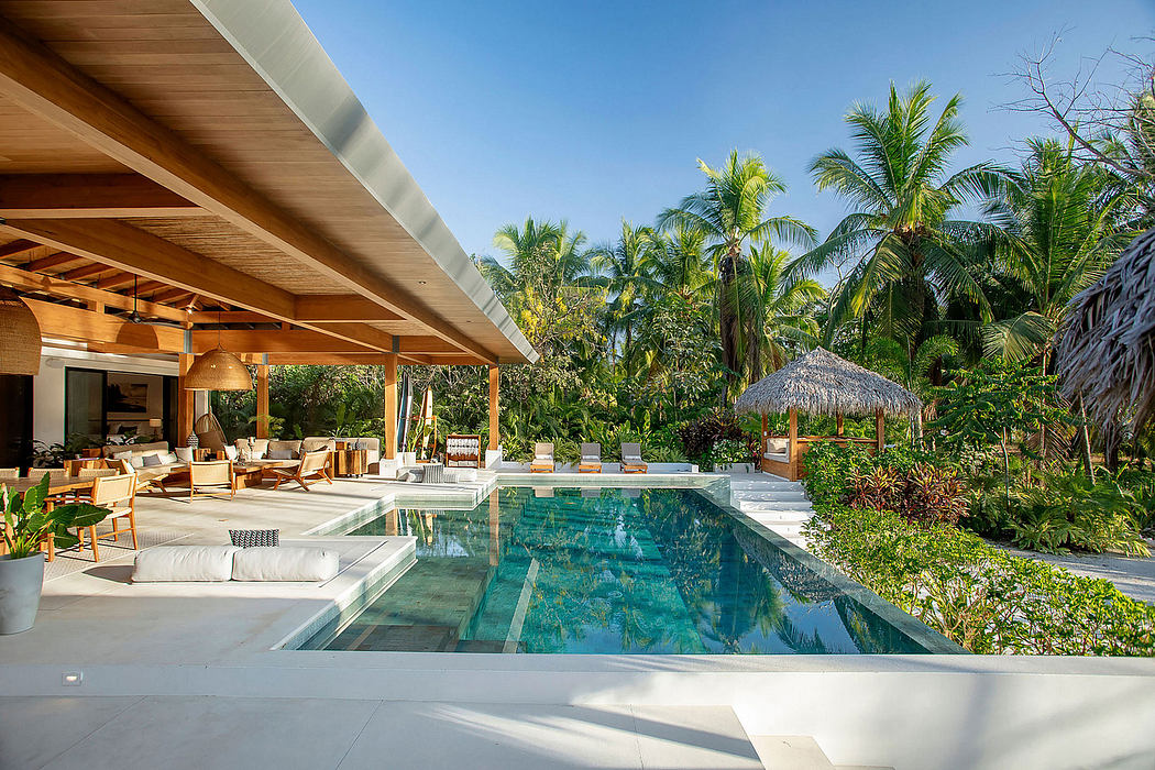 Luxurious tropical villa with thatched roof, infinity pool, and lush vegetation.
