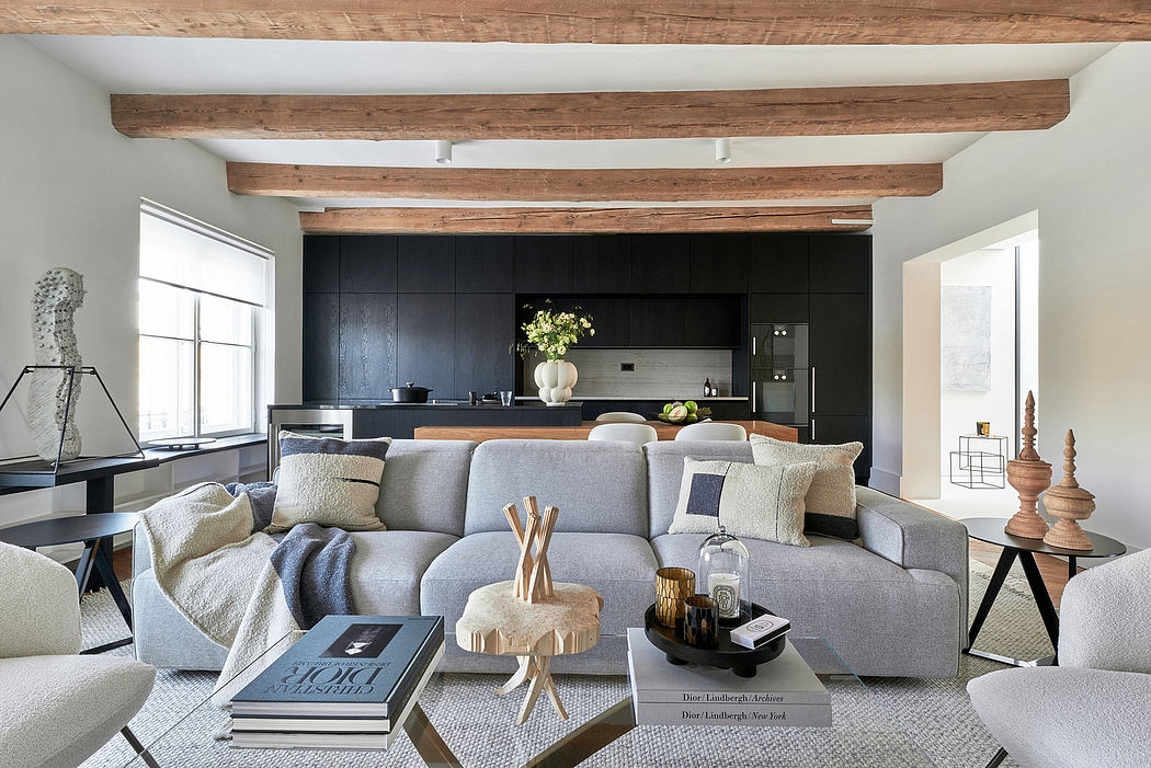 Spacious living area with exposed wooden beams, modern kitchen, and cozy gray sofa.