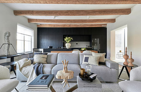 Spacious living area with exposed wooden beams, modern kitchen, and cozy gray sofa.