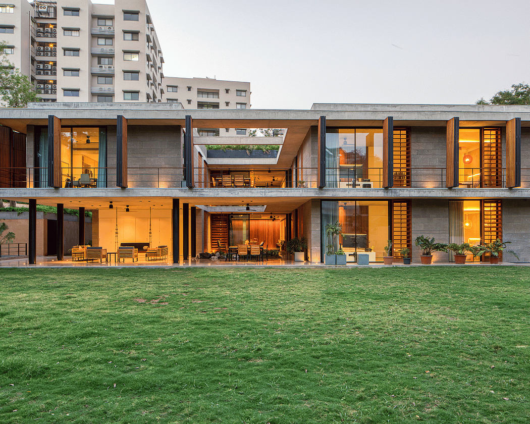 A modern, multi-story building with a sleek concrete facade, surrounded by a lush green lawn.
