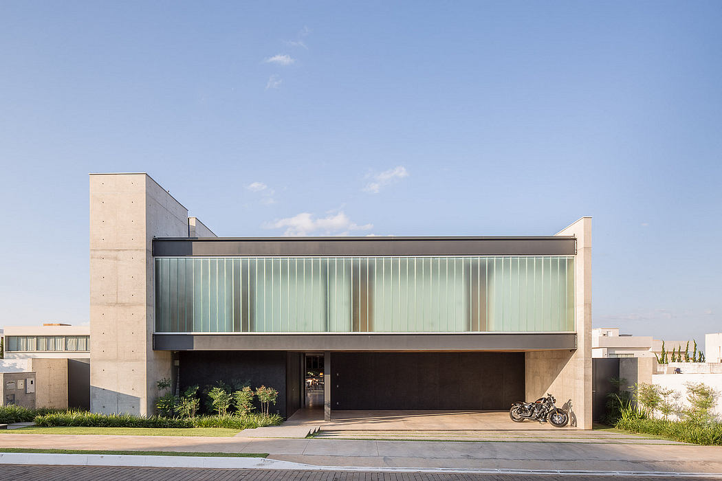 Modern, angular building with glass facade and concrete accents. Recessed entryway and bike parked outside.
