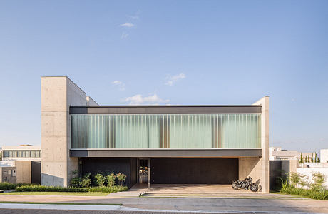 Modern, angular building with glass facade and concrete accents. Recessed entryway and bike parked outside.