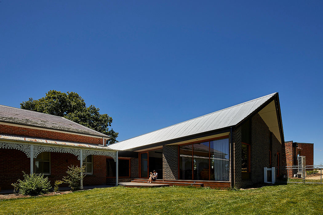 A modern farmhouse-style building with large windows, brick exterior, and metal roof.