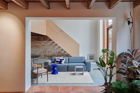 Cozy living room with rustic wooden beams, modern sectional sofa, and lush plant decor.