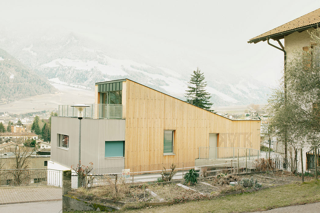 Modern wooden facade with large windows, set against a snowy mountain backdrop.