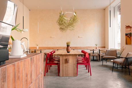 A cozy dining room with rustic wooden furniture, bold red chairs, and a striking moss-covered chandelier.