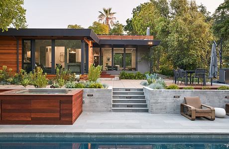 A modern, open-concept home with wood, stone, and glass elements, surrounded by lush greenery.