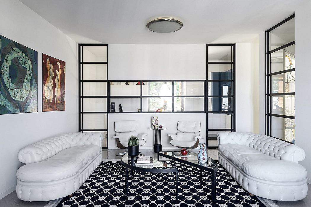 Modern living room with white Chesterfield-style sofas, black geometric rug, and metal shelving.