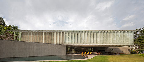 Striking modern building with a sleek, glass-enclosed facade and a serene pool in the foreground.