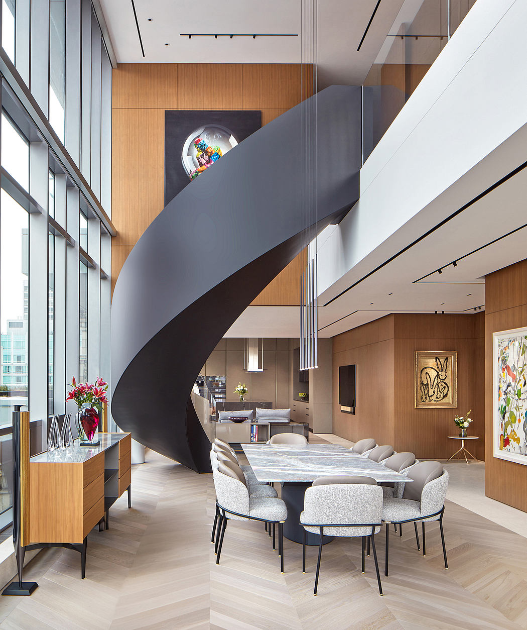 Sleek, modern dining room with curving staircase, wood paneling, and abstract artwork.