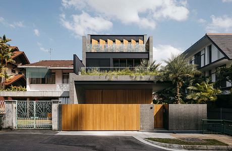 Striking modern architecture with wooden accents, greenery, and a raised rooftop structure.