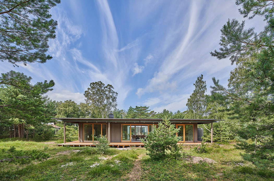 A modern, single-story cabin with large windows and a wooden exterior, surrounded by lush greenery.