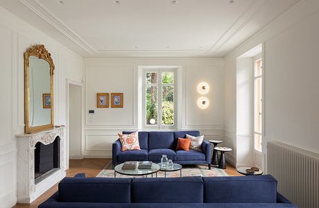 Inviting living room with ornate mirror, plush navy sofa, and garden view through window.