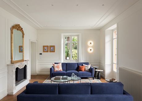 Inviting living room with ornate mirror, plush navy sofa, and garden view through window.