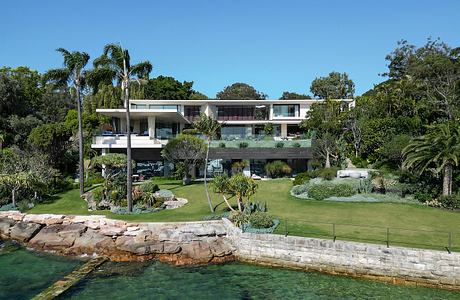 Modern, multi-level beachside residence with lush tropical landscaping and glass facade.