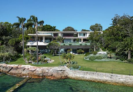 Modern, multi-level beachside residence with lush tropical landscaping and glass facade.