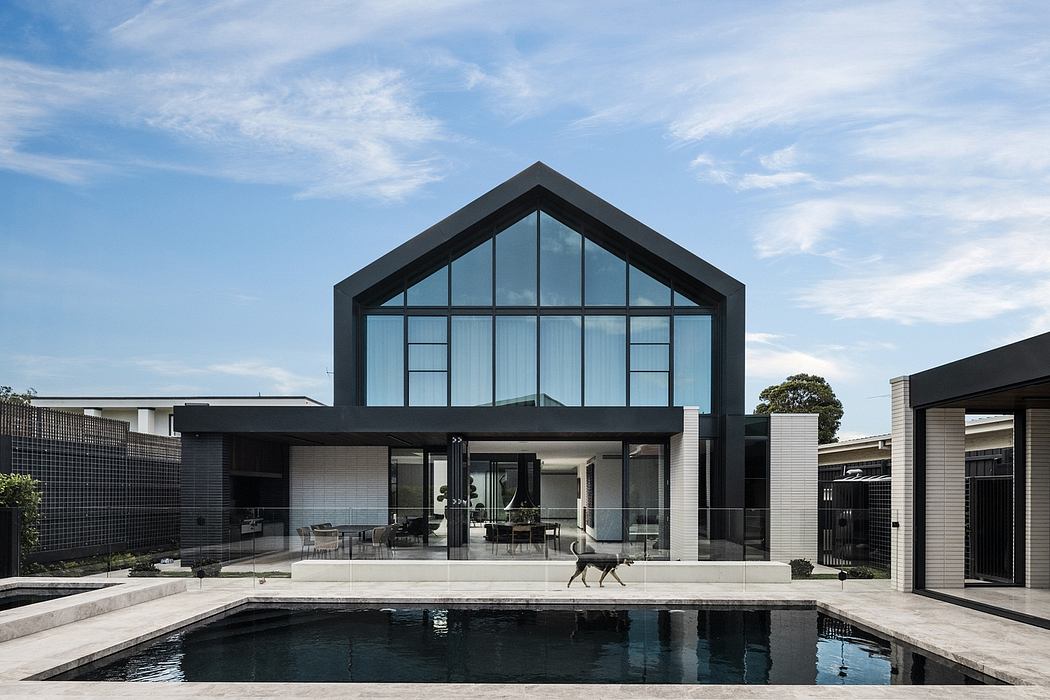 Modern architectural design with large glass windows, sleek black exterior, and a pool.