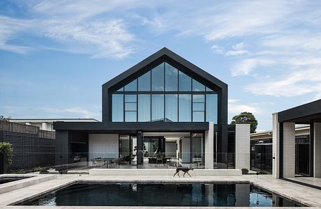 Modern architectural design with large glass windows, sleek black exterior, and a pool.