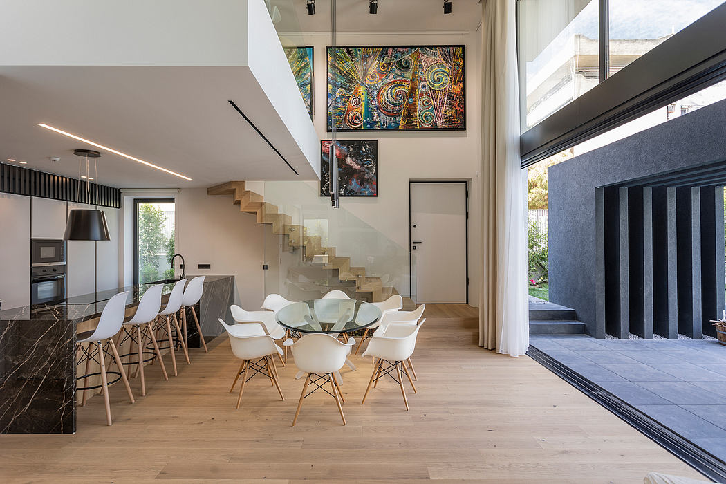 A modern, open-concept home with minimalist furniture, striking artwork, and a sleek staircase.