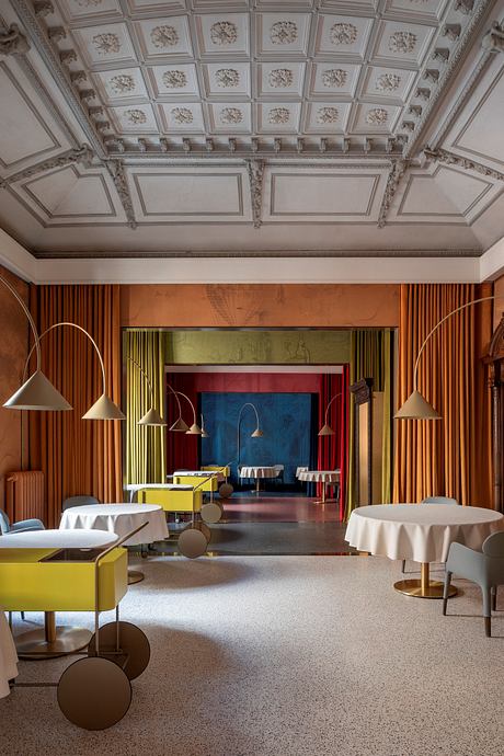 Ornate ceiling with intricate designs, contrasting with modern, colorful furnishings.