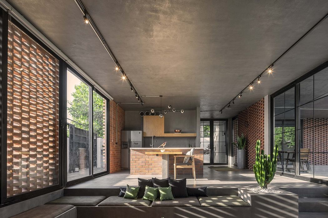 An open-concept modern living space with exposed brick walls, floor-to-ceiling windows, and track lighting.