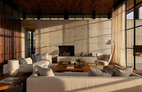 Cozy living space with textured concrete walls, wood-beamed ceiling, and plush furnishings.