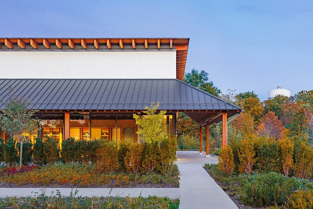 A modern, wooden-roofed building surrounded by a vibrant autumn landscape and a walkway.